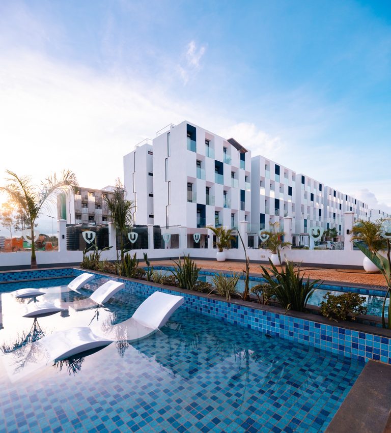 Swimming pool with white sun loungers and apartment blocks behind, Tatu City