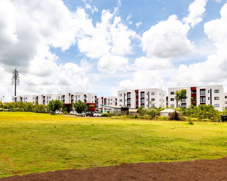 Wide mowed lawn field with apartment blocks visible in the distance, Tatu City