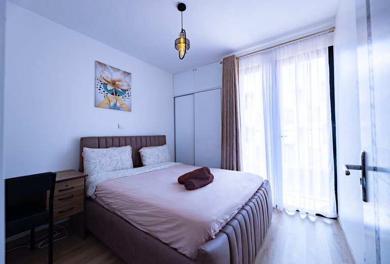Bedroom with the bed, a nightstand and a curtained balcony door, The Bloom, Tatu City