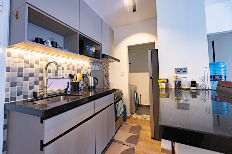 Kitchen counter with a kettle, spice jars and mosaic tile backsplash, hallway door beyond, The Bloom, Tatu City