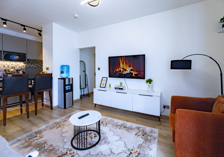 Living room TV wall seen past two dark bar stools in the foreground, The Bloom, Tatu City