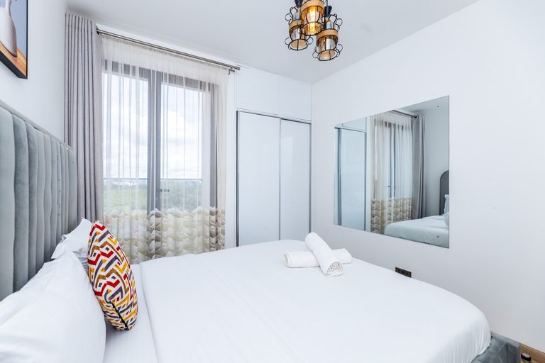 Grey tufted bed reflected in a wall mirror, The Deco, Tatu City