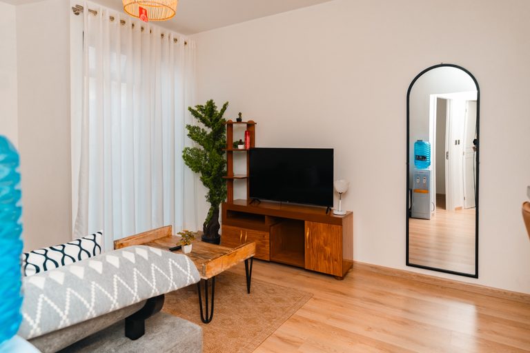 Sofa facing a wall mounted TV with a tall arched mirror nearby, The Driftwood, Tatu City