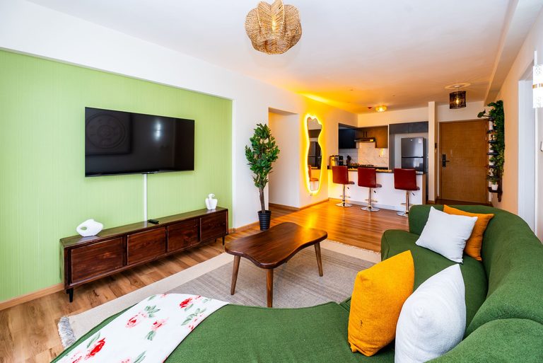 living room with sofa, tv and a tall mirror by the kitchen, The Emerald, Garden City