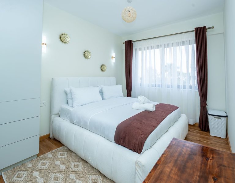 bedroom with a large bed, curtains and wall decor, The Emerald, Garden City