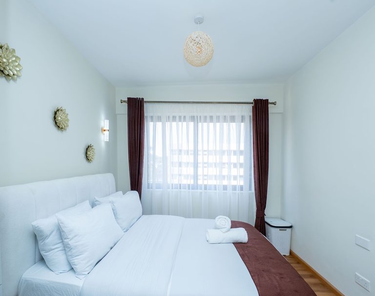 bedroom bed facing a curtained window, The Emerald, Garden City