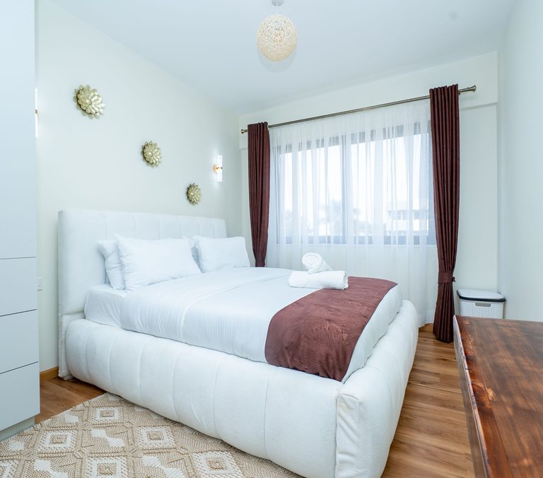 wide view of the bedroom bed, rug and window, The Emerald, Garden City