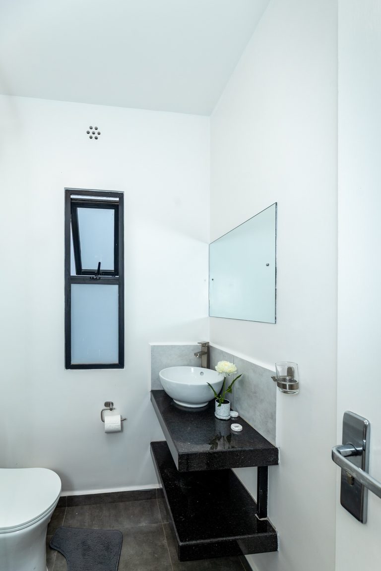 Bathroom with toilet, black floating vanity, round white sink and a tall window, The Gallery, Tatu City