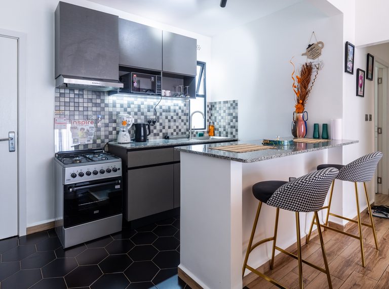 Kitchen wide view with cooker, breakfast bar and black hexagon floor tile, The Gallery, Tatu City