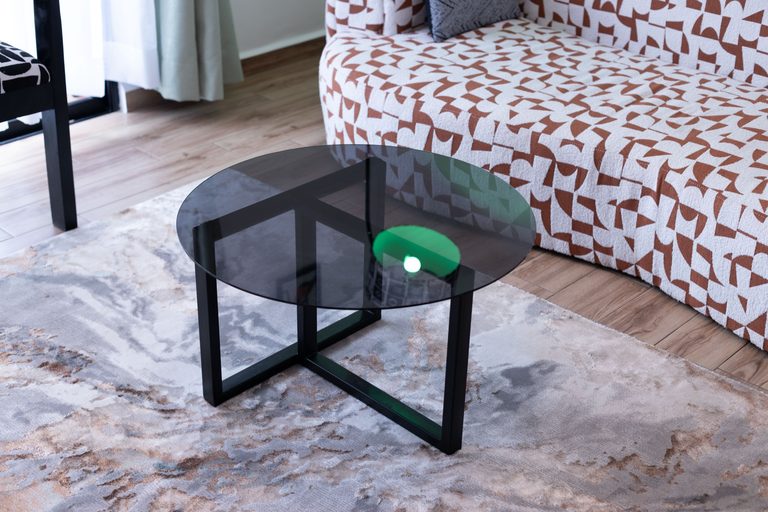 Round tinted glass coffee table on an abstract patterned rug, The Gallery, Tatu City