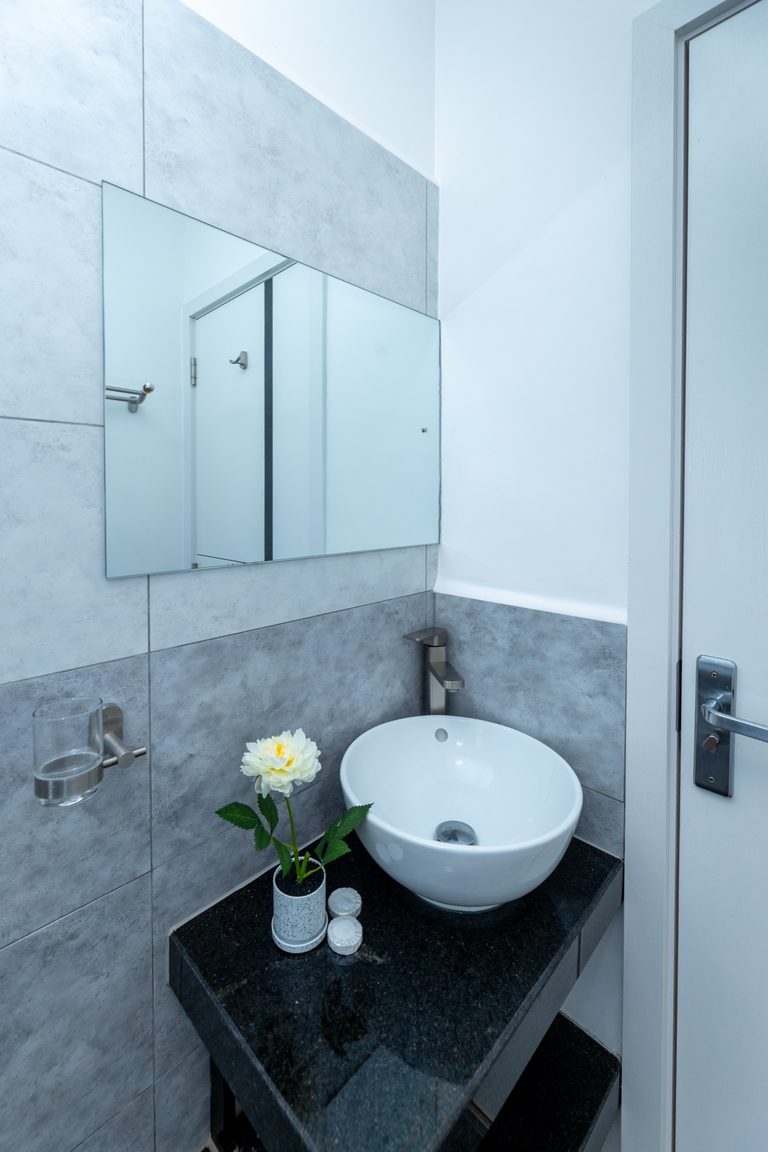 Second bathroom with a black floating vanity, round sink and wall mirror, The Gallery, Tatu City
