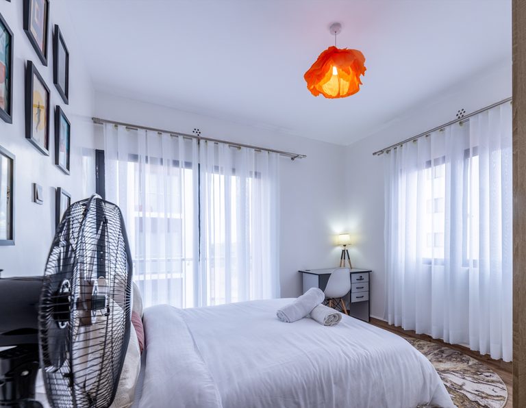 Second bedroom bed with an orange pendant light and a standing fan, The Gallery, Tatu City