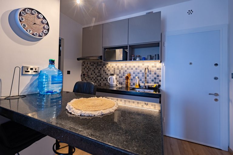 Kitchen breakfast bar with a wall clock, water bottle and a view to the entry door, The Graphite, Tatu City