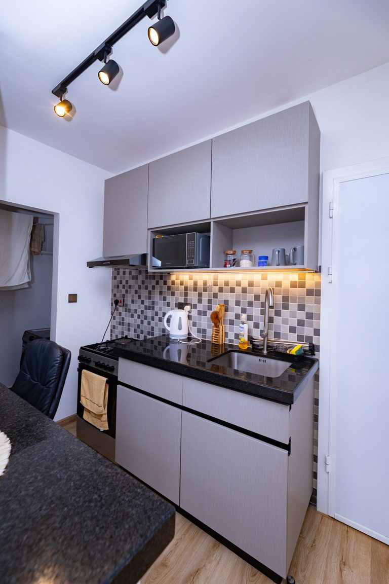 Kitchen counter with a gas stove, grey cabinets and a black dining chair, The Graphite, Tatu City