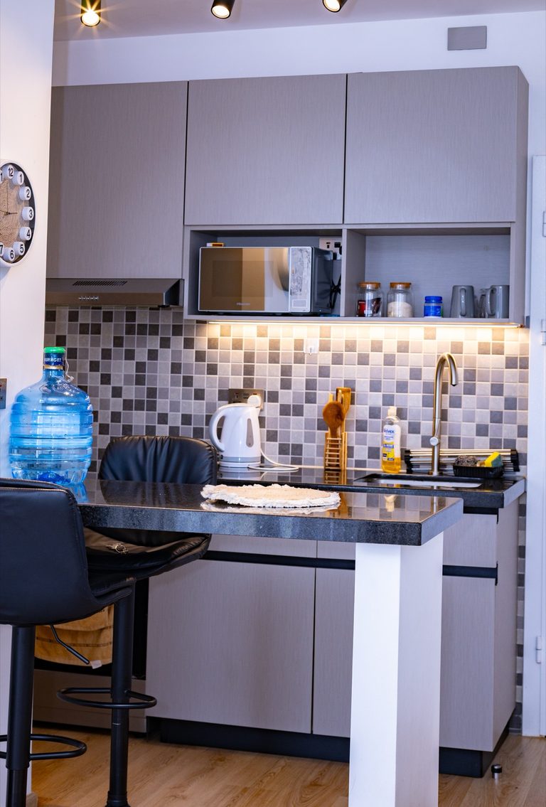 Wide kitchen view with a breakfast bar, two black stools and mosaic tile backsplash, The Graphite, Tatu City