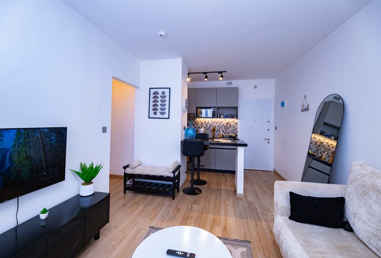 TV wall playing a video, black media console, a bolster bench and an arched floor mirror, The Graphite, Tatu City