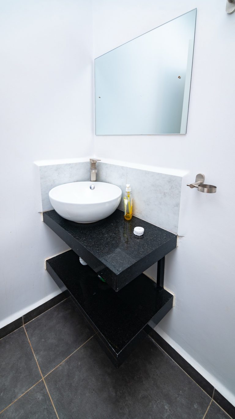 Small vessel sink on a dark counter against tiled wall, The Hearth, Tatu City