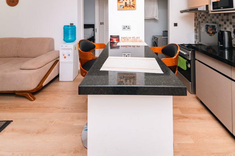 Kitchen bar counter with orange stools and a water dispenser nearby, The Hearth, Tatu City
