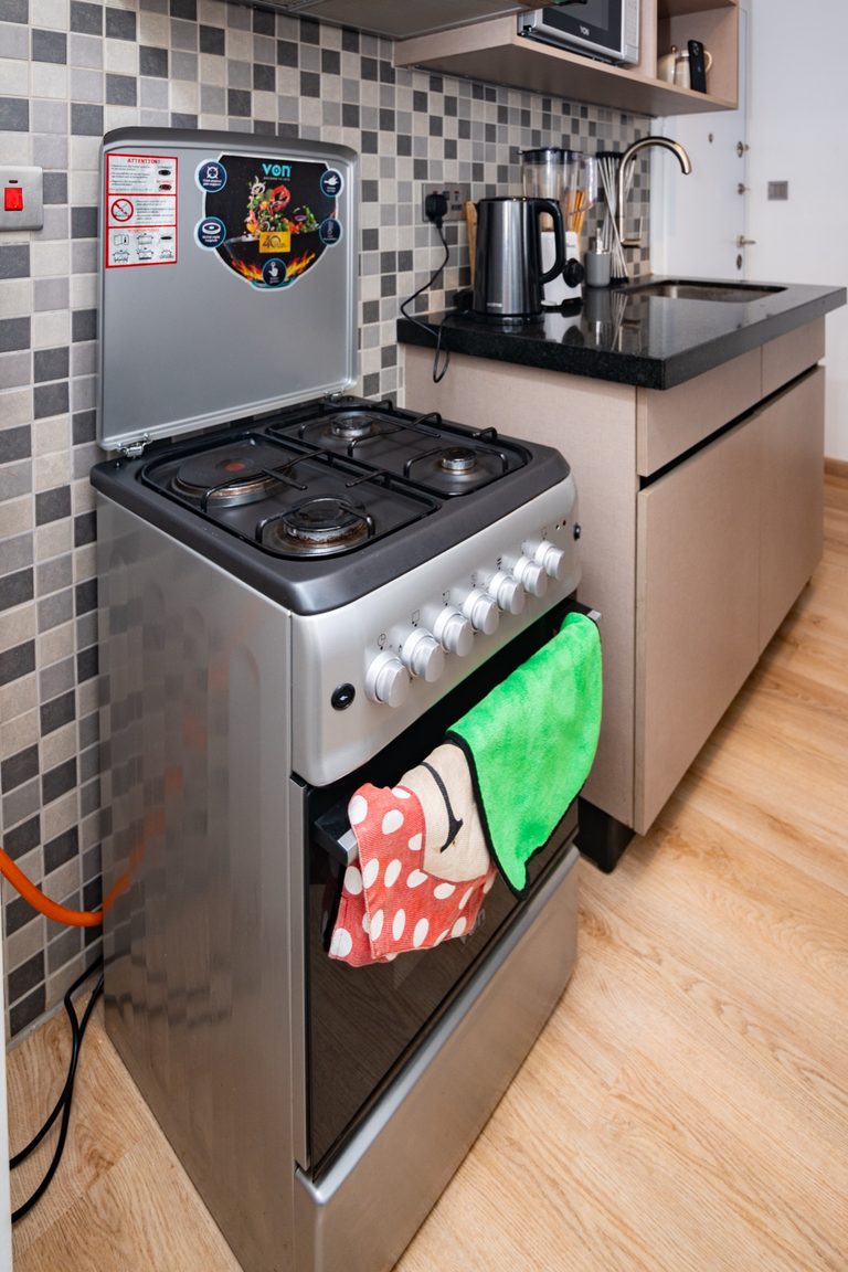 Gas stove with a green kitchen towel hanging on the oven door, The Hearth, Tatu City