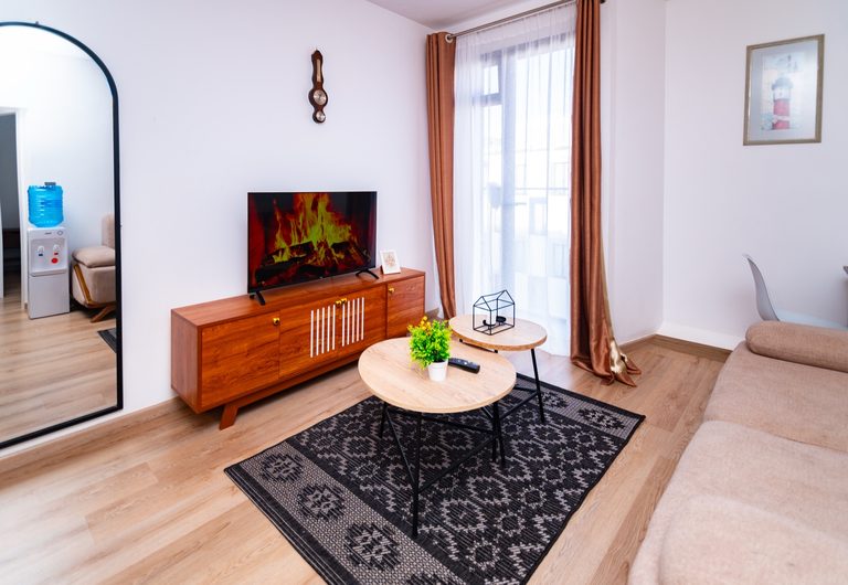 Living room with kitchen visible through the doorway, TV and mirror, The Hearth, Tatu City