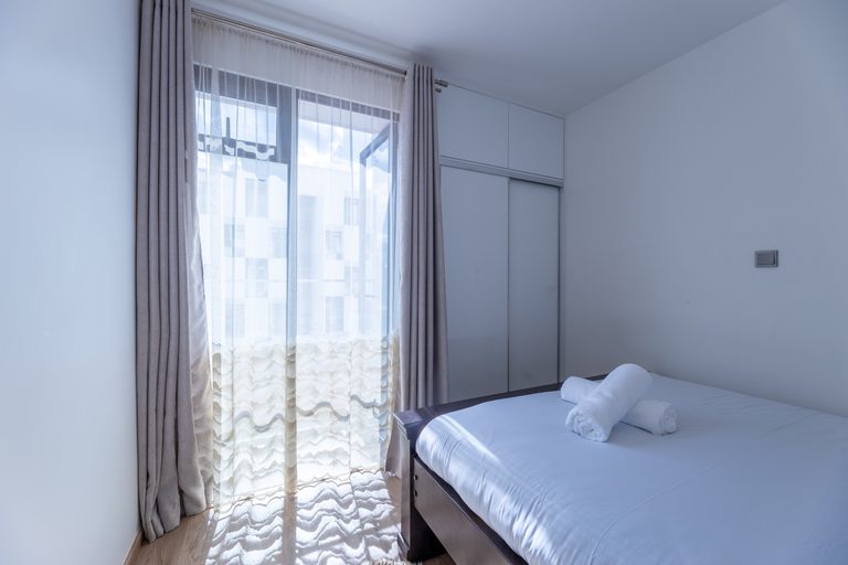 Bed positioned beside a curtained window, The Metro, Tatu City