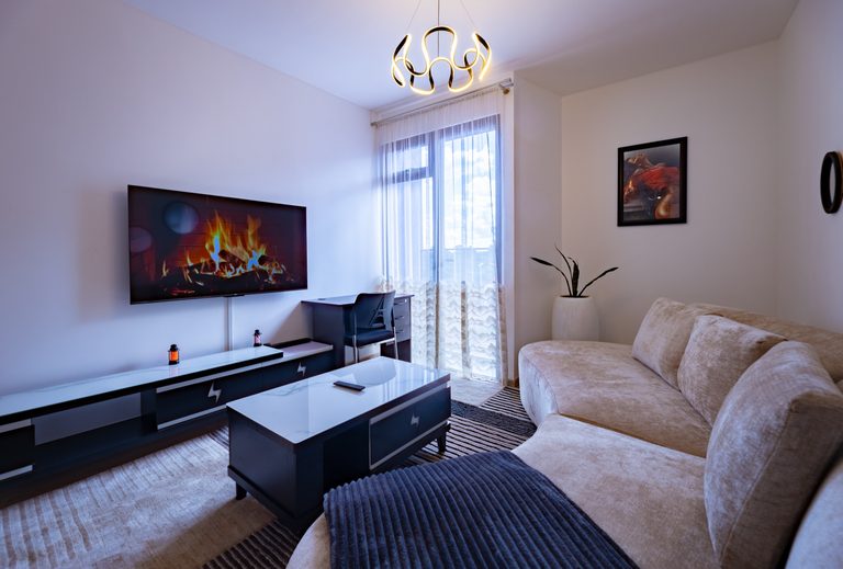 Sofa and coffee table facing a wall mounted TV, balcony door behind, The Metro, Tatu City