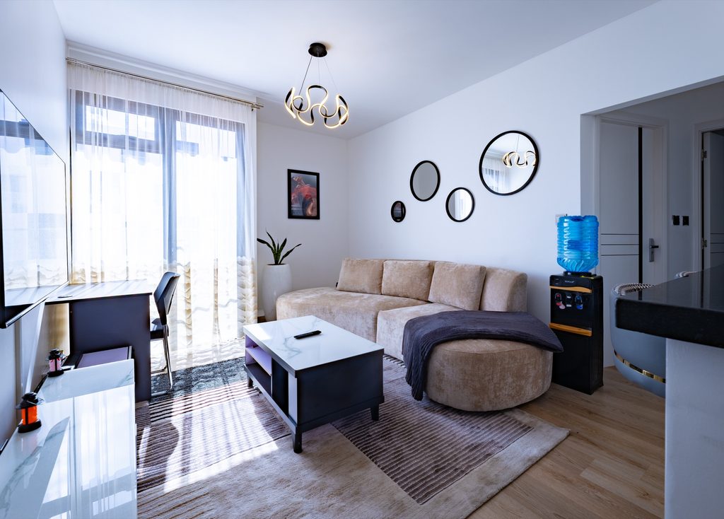Sofa and TV with round mirror cluster and sheer curtain over balcony door, The Metro, Tatu City