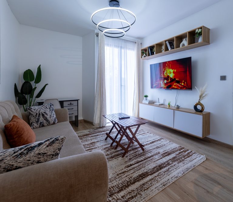 Full living room view with a ring pendant light, TV wall, coffee table and the kitchen beyond, The Tide, Tatu City