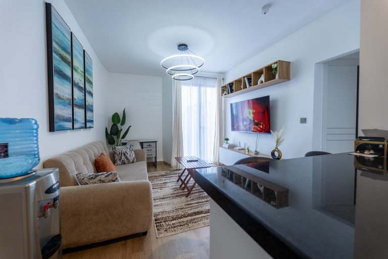 Wide view of the living room sofa, TV wall and art, seen past the kitchen counter, The Tide, Tatu City