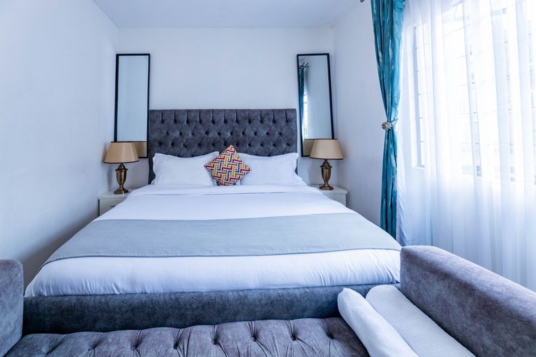Main bedroom grey tufted bed with a matching storage bench, The Velvet, Tatu City