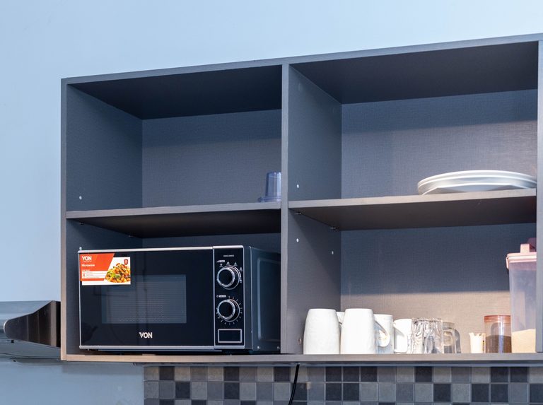 Open kitchen shelving with a microwave, oven and coffee mugs, The Velvet, Tatu City