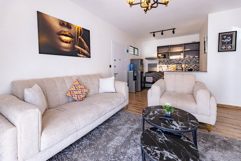 Cream armchair beside nested black marble coffee tables, The Velvet, Tatu City