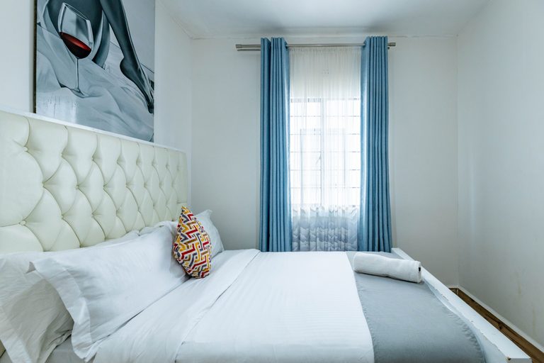 Second bedroom tufted headboard with light blue curtains and canvas art, The Velvet, Tatu City